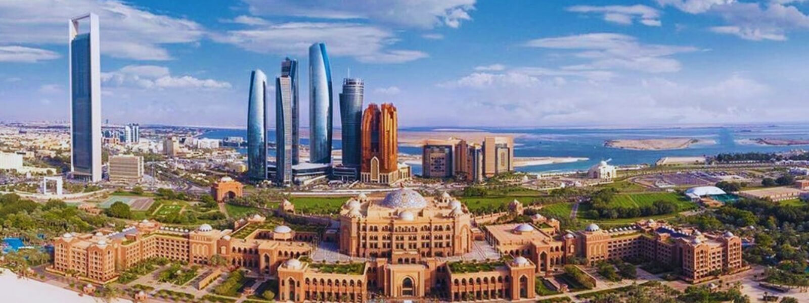 Aerial view of Abu Dhabi cityscape with towering skyscrapers, bustling streets, and a beautiful coastline.