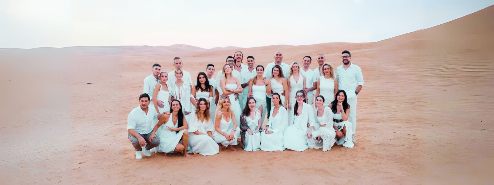 A group of people in white outfits standing in the desert under the scorching sun and making their tour memorable