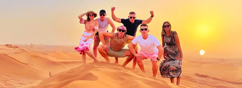Several people posing for a photo in the desert. They smile and stand close together, capturing a memorable moment in the arid landscape.