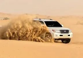 White SUV driving through the desert landscape under a clear blue sky.