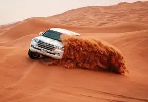A white SUV driving through the desert under a clear blue sky.
