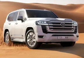 A SUV driving through the desert, showcasing its power and capability in the rugged terrain.
