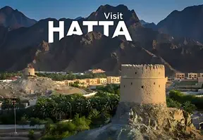 A scenic view of Hatta, Oman with mountains and a clear blue sky.