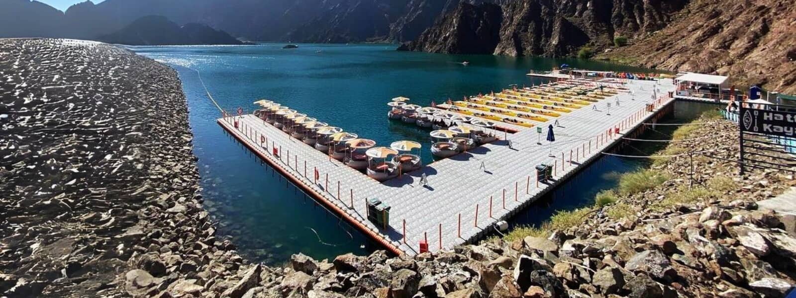 A serene boat dock with colorful umbrellas and rocks scattered in the water, creating a picturesque scene.