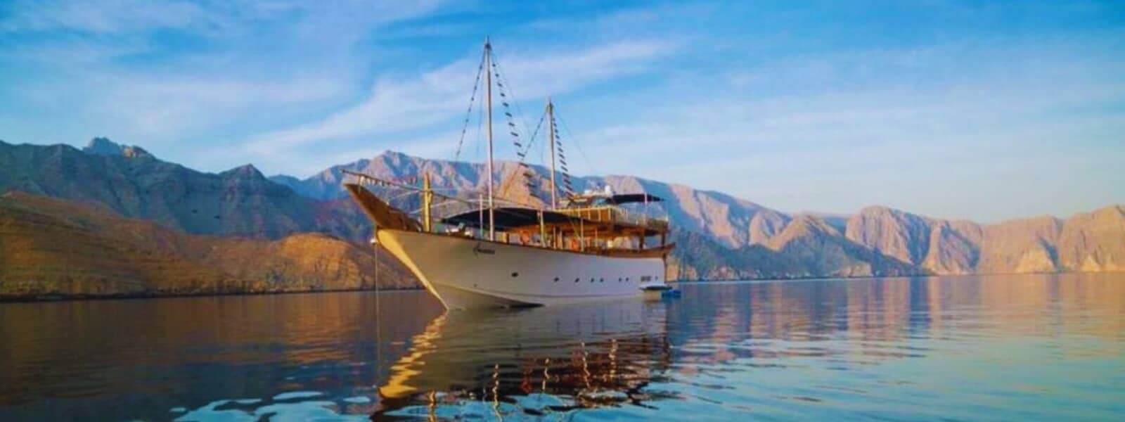A boat glides on the water, surrounded by majestic mountains.