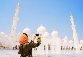 Woman capturing image of the white mosque on camera.