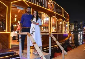 A couple smiling and posing for a photo on a boat, enjoying a scenic view of the water and the surrounding landscape.
