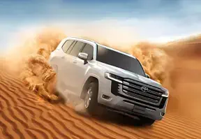 A Toyota Land Cruiser driving through the desert, showcasing its ruggedness and capability in harsh terrains.