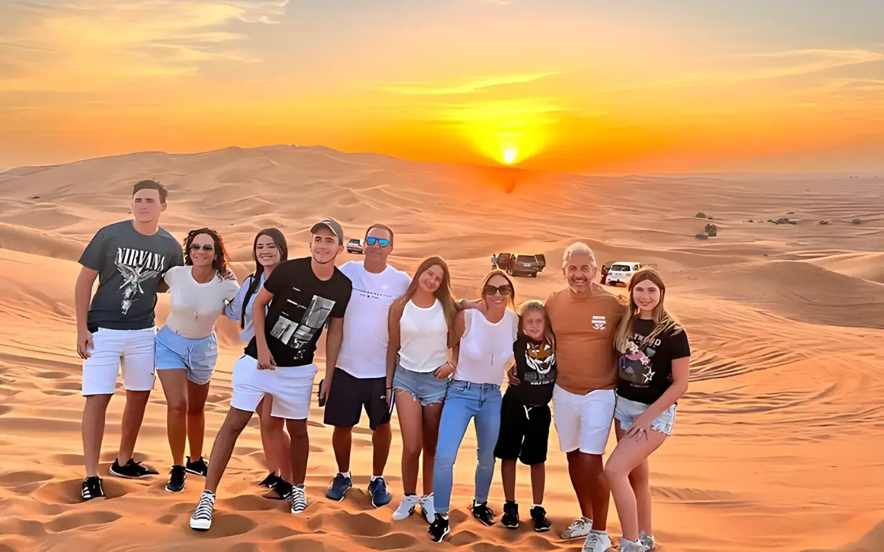 Several individuals standing in the desert as the sun sets in the background.